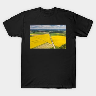 Agricultural landscape, fields of yellow colza and green grain under moody cloudy T-Shirt